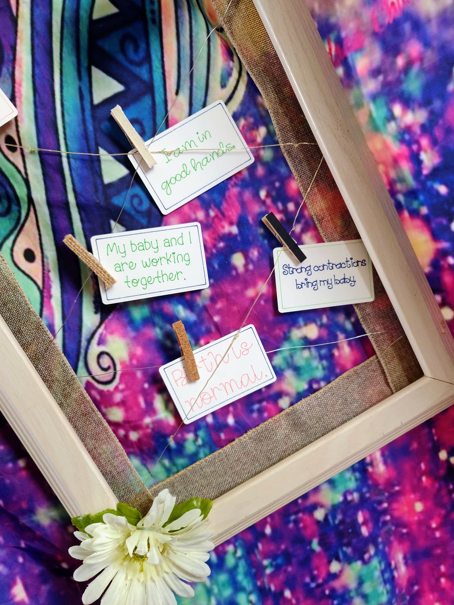 Photograph of several birth affirmation cards displayed artistically in a wood frame clipped to wires. The affirmations say: "I am in good hands." "My baby and I are working together." "Strong contractions bring my baby." and "Birth is normal."